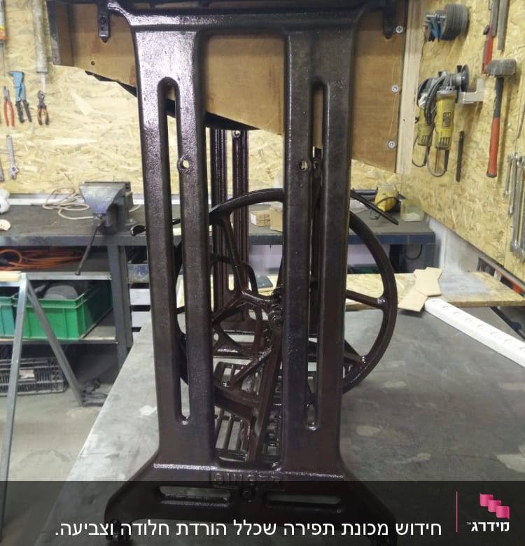 מסגרת מתכת של מכונת תפירה ישנה עם גלגלים